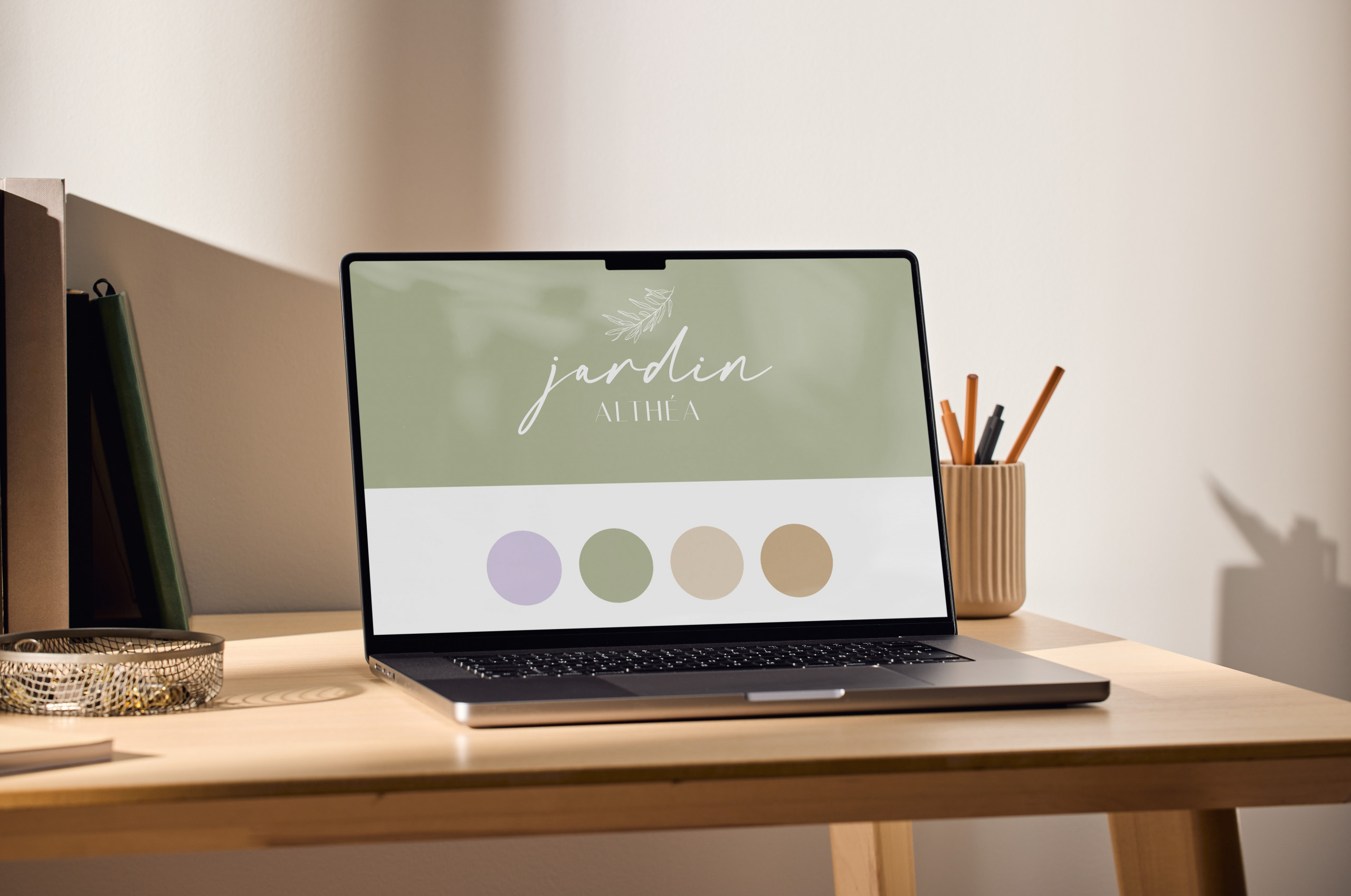 Bureau avec un ordinateur, un logo et une palette de couleur sur l'écran. Il y a un pot à crayon